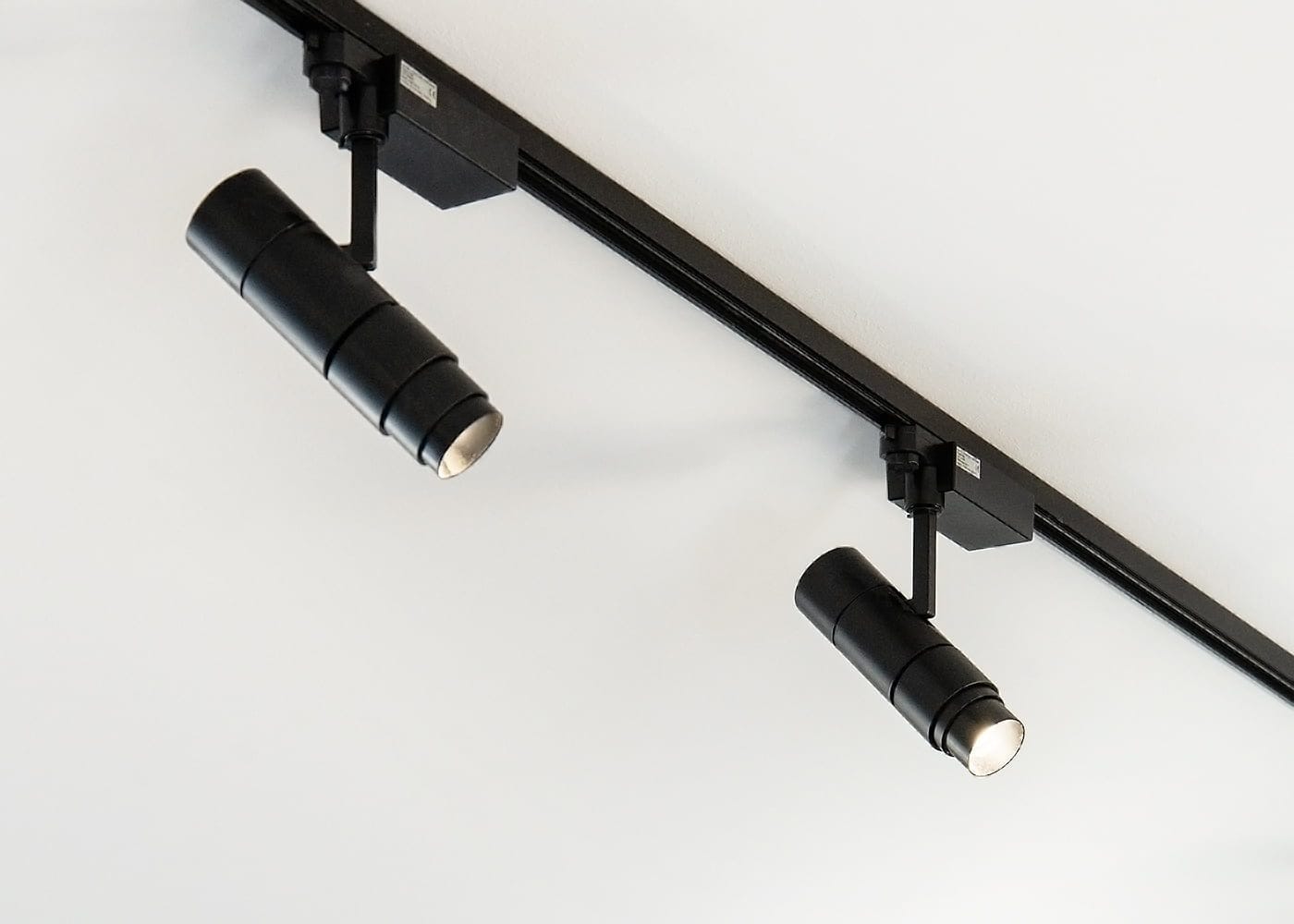 Two black LED track lights on a white ceiling, providing efficient, focused downward illumination to enhance the room's ambiance. Perfect modern lighting.