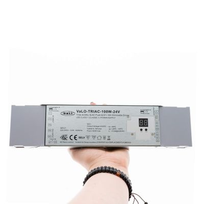 Close-up of a hand holding the VaLO TRIAC-100W-24V LED dimmer with digital display, which improves the energy efficiency of LED lighting.